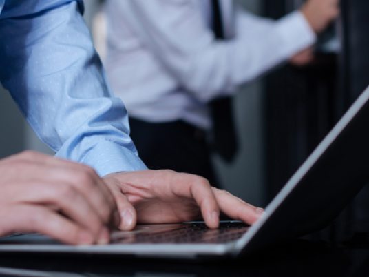 close-up of gentleman typing on laptop