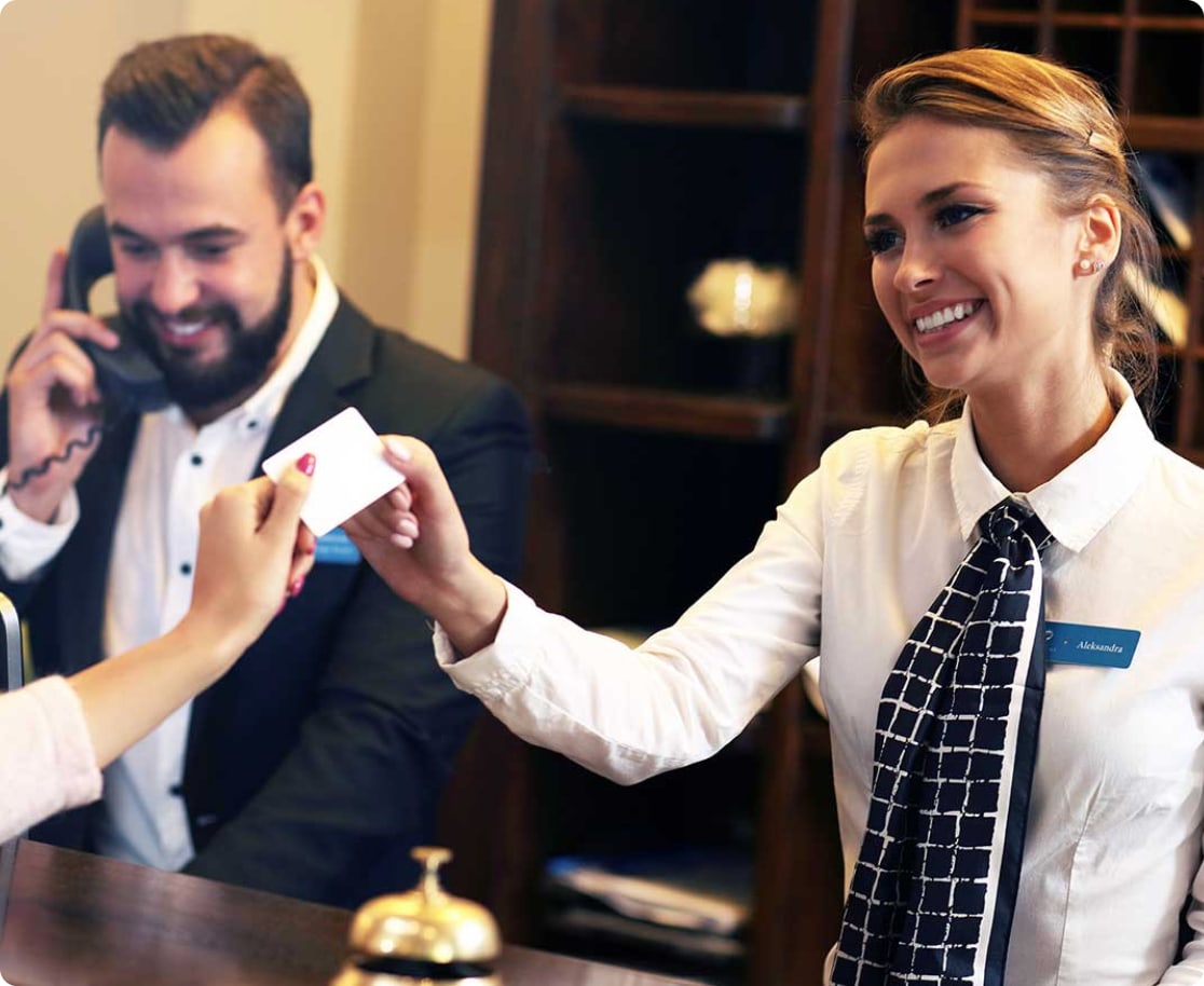 woman at hotel handing lady her credit card