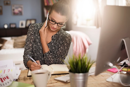 woman talking on phone and writing in journal