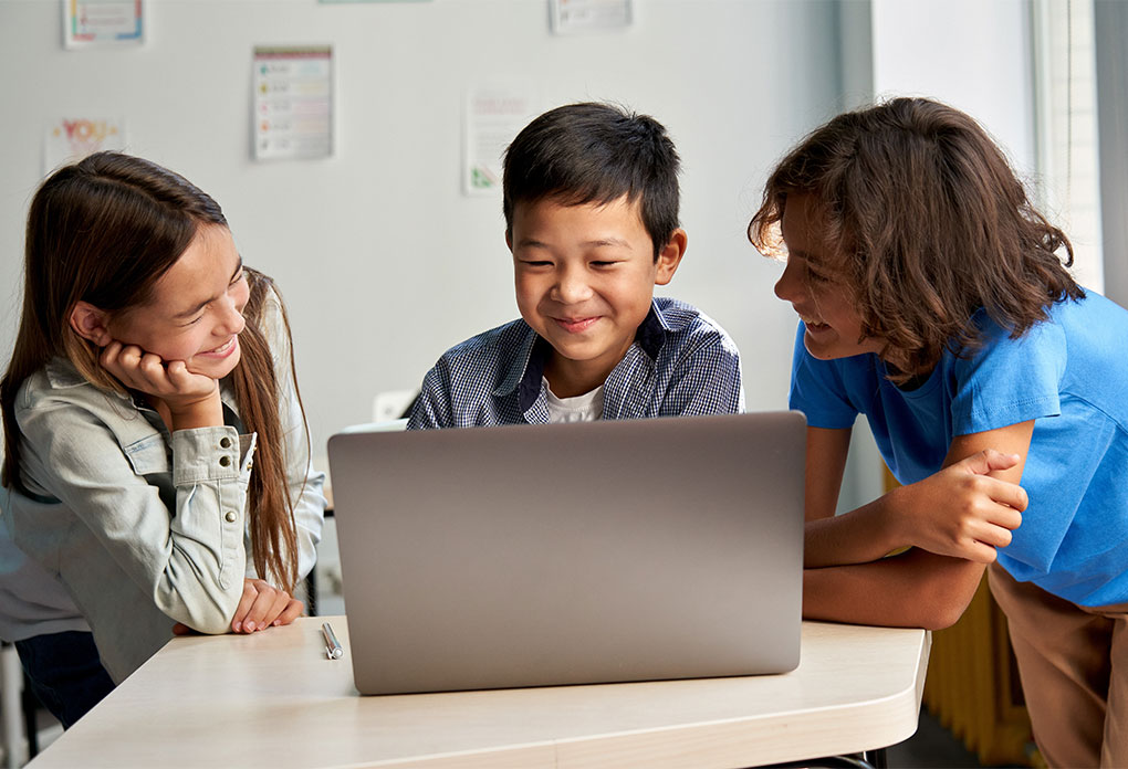 elementary school children using laptop in classroom